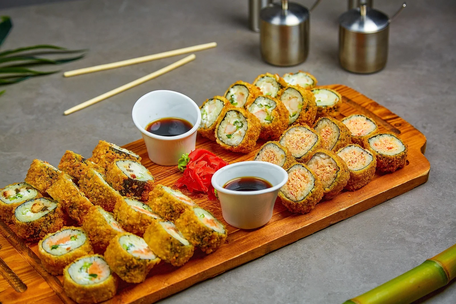 Crispy sushi rolls on a wooden board with dipping sauces