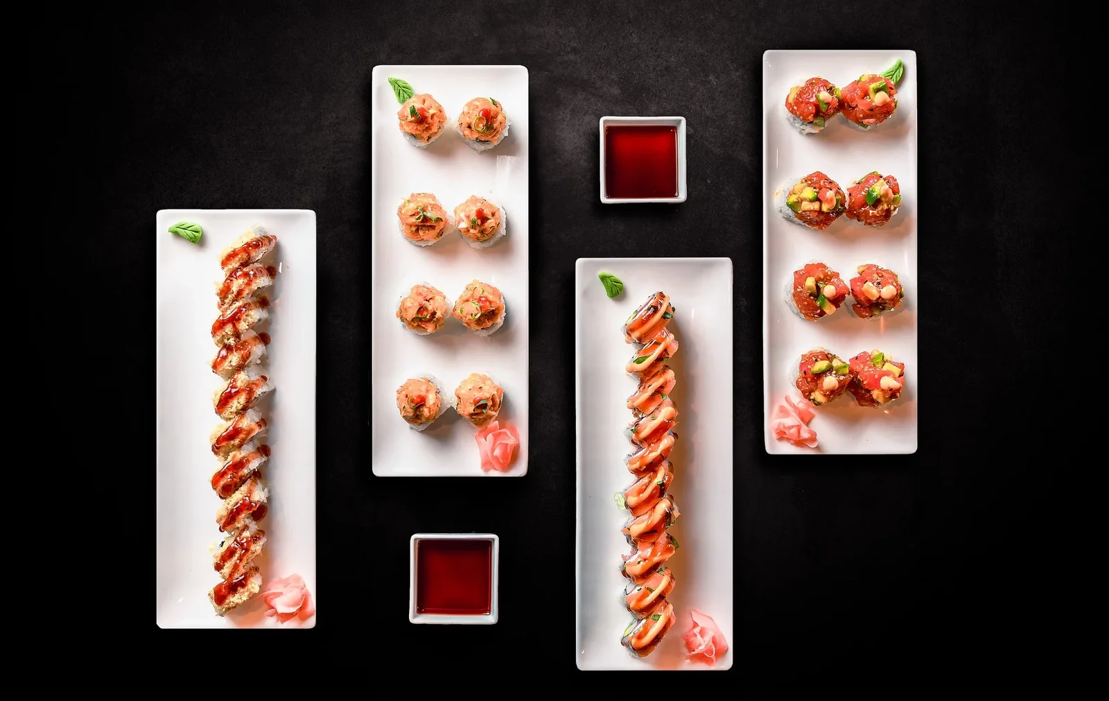 An overhead spread of sushi on white platters
